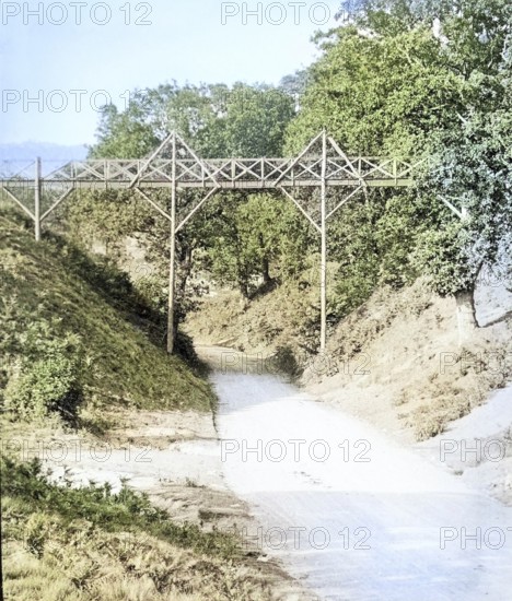 Colourised magic lantern slide of footbridge crossing the road at Wilford Hollows, Bromeswell,