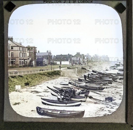 Colorised magic lantern slide by Poulton of boats on the beach in front of Esplanade buildings