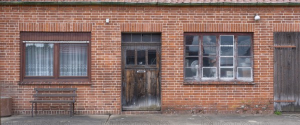View of the entrance area of an older residential building with a red brick workshop, Uenzen,