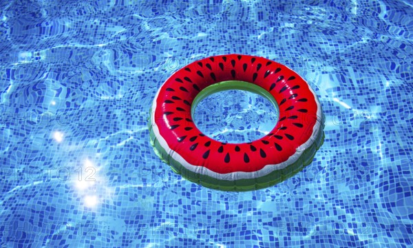 A bright ring-a float, with a watermelon, in the clear blue water of the pool, under the sunlight