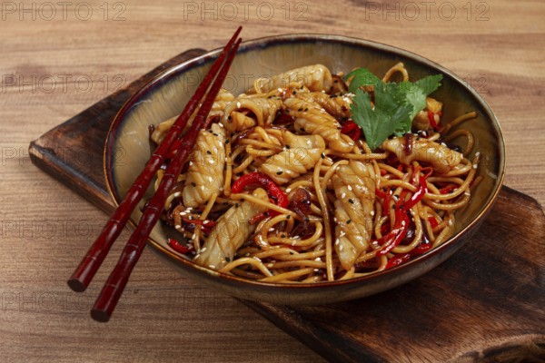 Udon noodles, with squid and vegetables, on a wooden table, homemade, no people