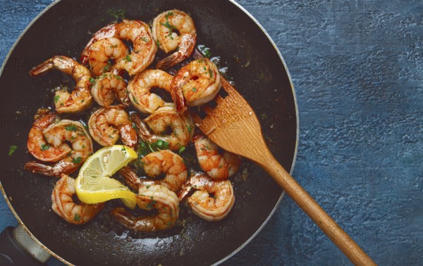 Fried tiger prawns, jumbo, in garlic sauce, in butter, with herbs, in a frying pan, homemade, no
