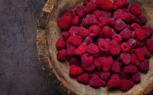 Fresh raspberries in a wooden bowl, food background, concept, food styling, on a dark table, top
