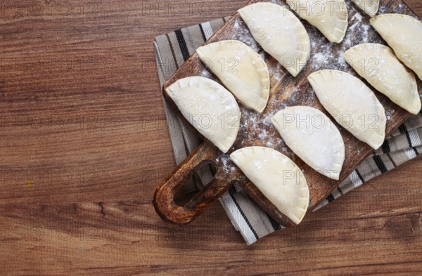 Traditional Polish dish, dumplings, raw, frozen, on a cutting board, wooden table, top view, no