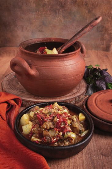 Chanakhi, a Georgian dish. in a clay pot, on a wooden table, stewed meat with vegetables, homemade,