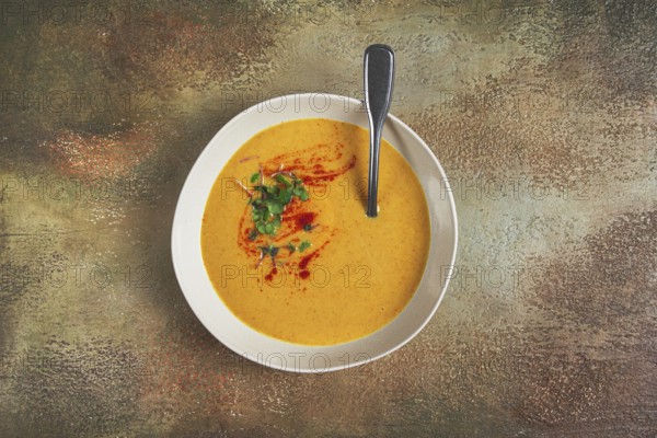 Pumpkin cream soup, in a white bowl on a textured background, top view, homemade, no people, rustic