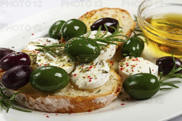 A plate with a snack, ciabatta bread with cheese and olives, olive oil, spices and herbs, top view,