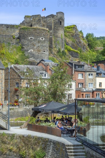 Tourists at restaurant along the river Ourthe and ruined castle in the city La Roche-en-Ardenne,