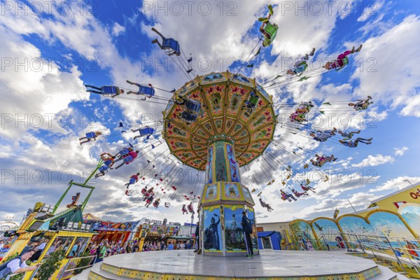 Chain carousel in motion in front of a white-blue sky, Theresienwiese, Oktoberfest, Munich, Upper