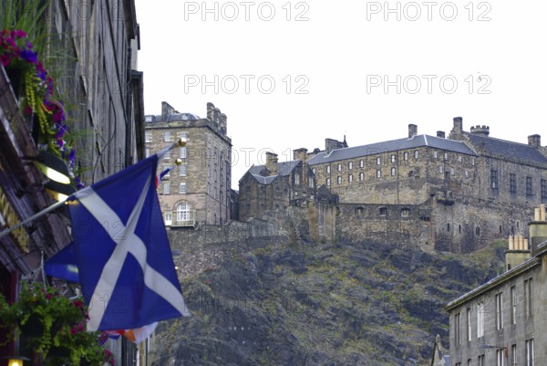 Scottish castle on a hill surrounded by buildings and a Scottish flag, Old Town, Edinburgh,