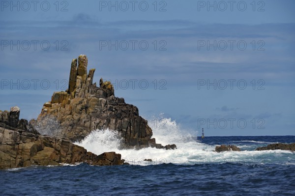 Rough sea with waves crashing against rocks under a blue sky, Isles of Scilly, Cornwall, Great
