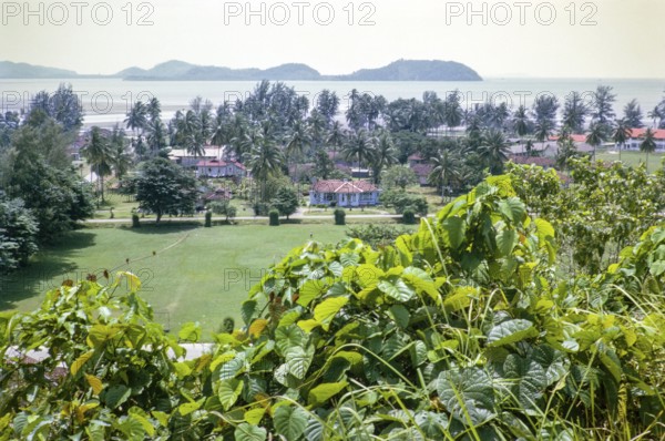 View to offshore island over houses in coastal area near Mersing, Johor, Malaya, Malaysia, south