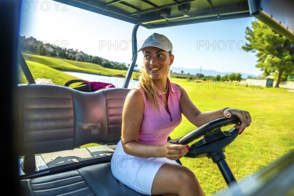 Smiling female golfer driving a golf cart on a sunny golf course, enjoying a leisurely day of