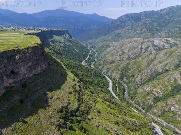 View of a picturesque valley with a river, surrounded by high mountains and lush vegetation under a