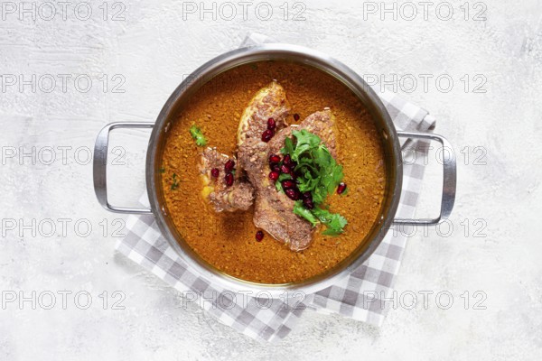 Fesenjan, an Iranian dish, stewed chicken, in a nut-pomegranate sauce, in a saucepan, light