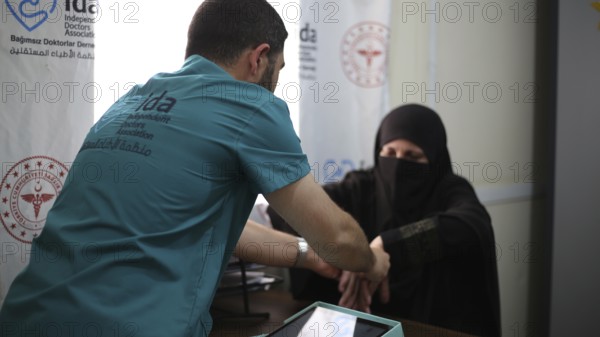 A doctor examining a woman inside a mobile medical point dedicated to treating Syrian refugees.