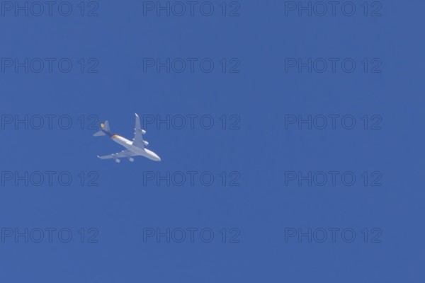 Boeing 747 jumbo jet cargo aircraft of UPS United Postal Service flying in a blue sky, England,