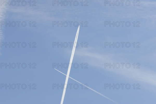 Two jet passenger aircraft with vapour trails or contrails flying in a blue sky crossing making a