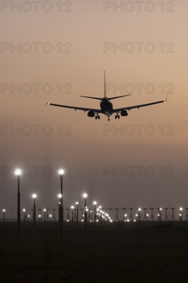 Boeing 737 jet passenger aircraft of Ryanair airlines landing over runway lights at sunset, London