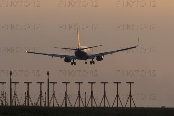 Boeing 737 jet passenger aircraft of Ryanair airlines landing over runway lights at sunset, London