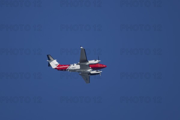 Beech King Air 350 light aircraft of the UK HM Coastguard flying in a blue sky, England, United