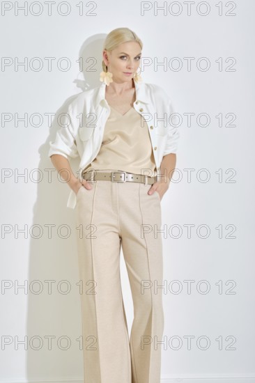 A model showcases a chic outfit featuring a light-colored top and tailored trousers, complemented