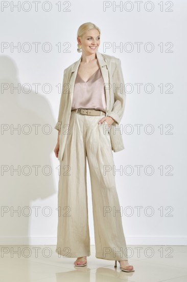 A confident woman stands in a well-lit indoor area, wearing casual outfit featuring a light-hued