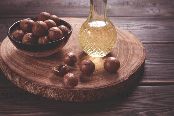 Bottle of macadamia oil, on a wooden board, with macadamia nuts, wooden background, selective