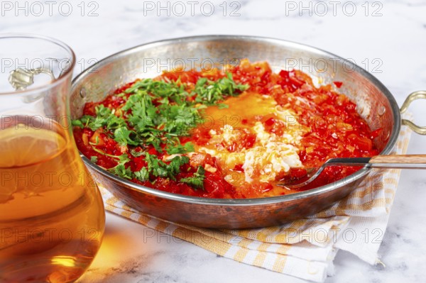 Traditional Turkish dish, scrambled eggs with tomatoes, Menemen, with herbs, in a frying pan,