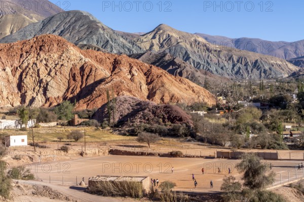 Young people playing football, with coloured hills in the background, erosion, Purmamarca, Jujuy,