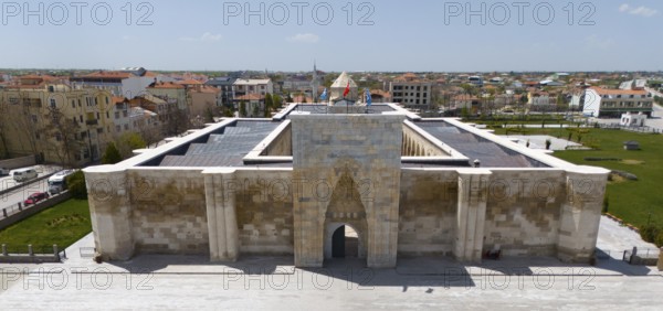Frontal view of a medieval caravanserai with imposing archway in urban surroundings, aerial view,