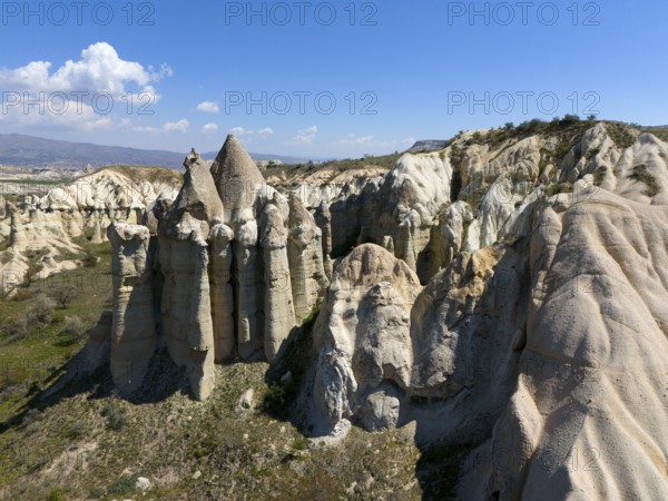 Impressive rock formations under a blue sky in a dry, rocky landscape, aerial view, Love Valley,