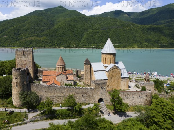 Medieval castle landscape by a body of water with green hills and peaceful atmosphere, aerial view,