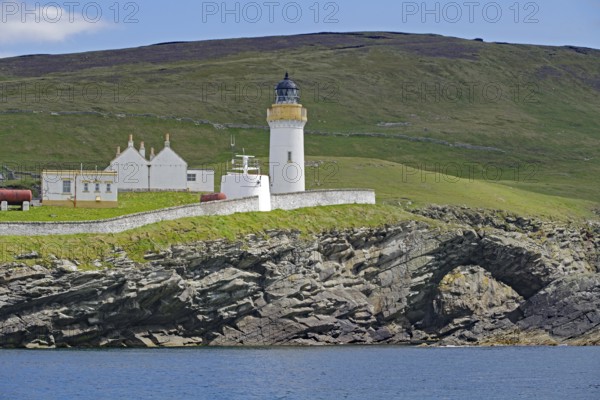Lighthouse and building on green coastal landscape above the sea, Stevenson family, Noss, Shetland