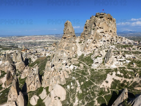 Rocky landscape with ancient rock structures under a clear blue sky in Cappadocia, aerial view,