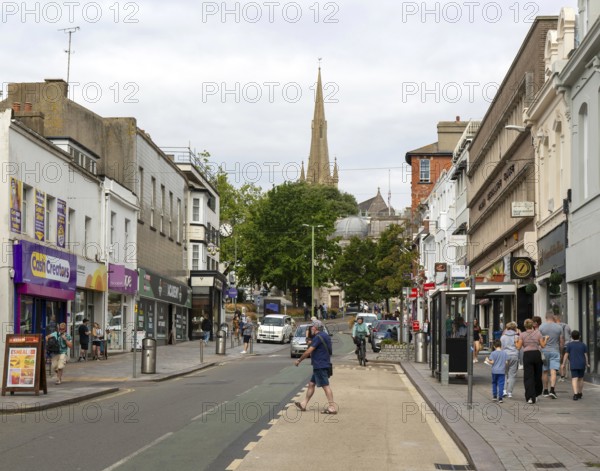 Shops in street of historic buildings, Union Street, Torquay, Devon, England, UK view to church