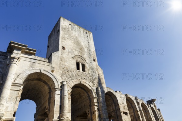 Roman amphitheatre in front of a blue sky, sunbeams, Arles, Provence, France