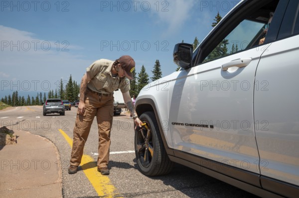 Colorado Springs, Colorado - A Pikes Peak ranger checks the temperature of brakes on a car