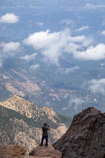 Colorado Springs, Colorado - A man takes photos from the rocks just below the summit of Pikes Peak,
