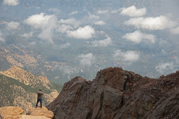 Colorado Springs, Colorado - A man takes photos from the rocks just below the summit of Pikes Peak,