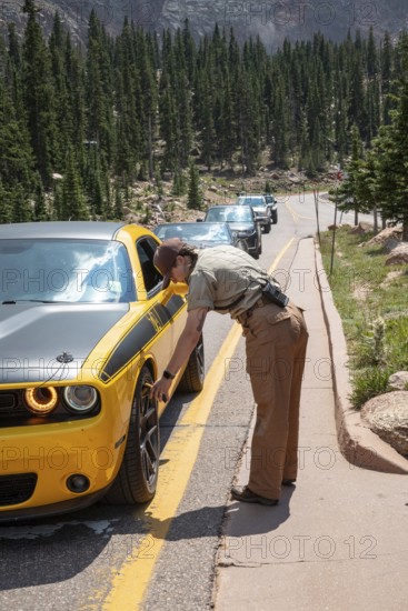 Colorado Springs, Colorado - A Pikes Peak ranger checks the temperature of brakes on a car