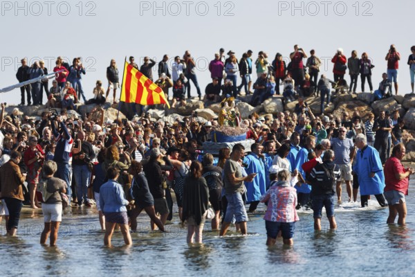 Pilgrimage, procession by the sea, pilgrims walking through water, statue of the Virgin Mary,