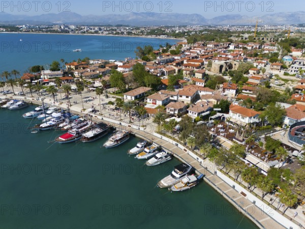 Scenic harbour with boats and palm trees along the coastline of a town, aerial view, harbour, Side,