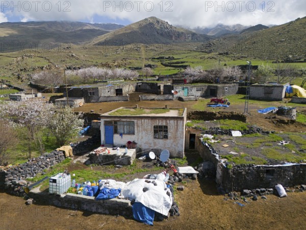 Rural village with simple houses and lots of greenery in mountainous terrain under a cloudy sky,