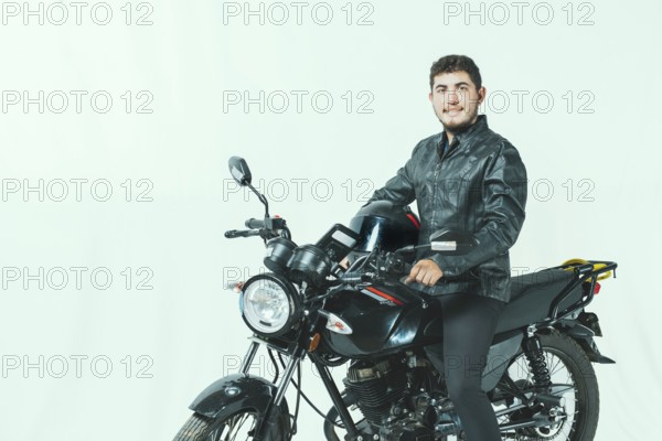 Smiling motorcyclist sitting on his motorcycle holding helmet, isolated. Portrait of handsome biker