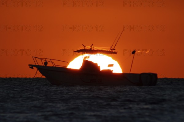 The sun rises behind a boat on the Costa Rei, a coastal stretch of the Italian Mediterranean island