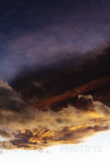 A stunning display of clouds during sunset showcases vibrant orange and deep purple colors fading