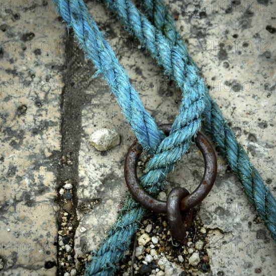 A close-up view reveals a vibrant blue rope intricately intertwined with a metal ring, resting on a