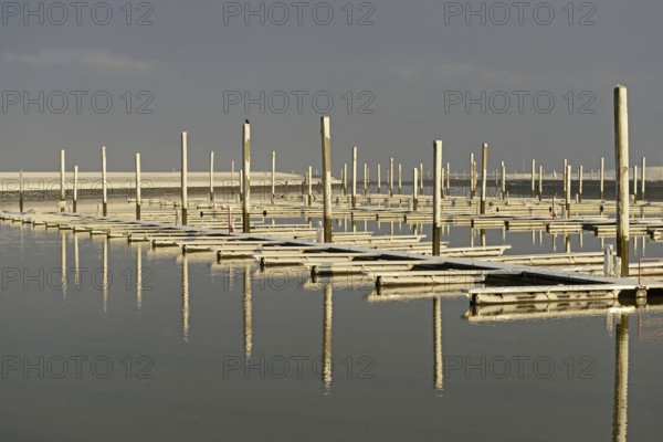 Winter day, onset of winter, morning sun shining on the snow-covered jetties in the marina, North