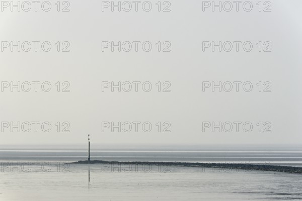 North Sea coast, cloudy winter day, Wadden Sea at low tide, stone groyne with sea mark, North Sea,